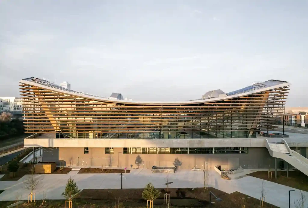 Timber Aquatics Center in Paris, designed by VenhoevenCS and Ateliers 2/3/4, features an undulating timber facade for the 2024 Olympic Games.