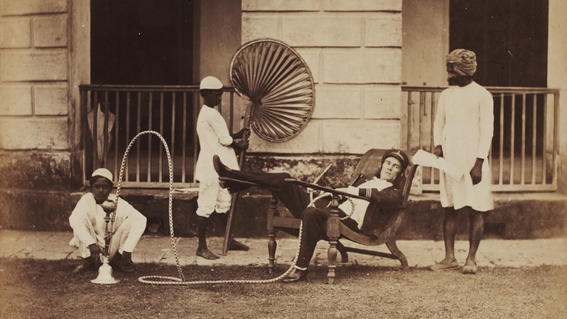 A colonial master on the planter’s chair, symbolizing power, as native servants serve—Bengal Presidency, late 19th century.